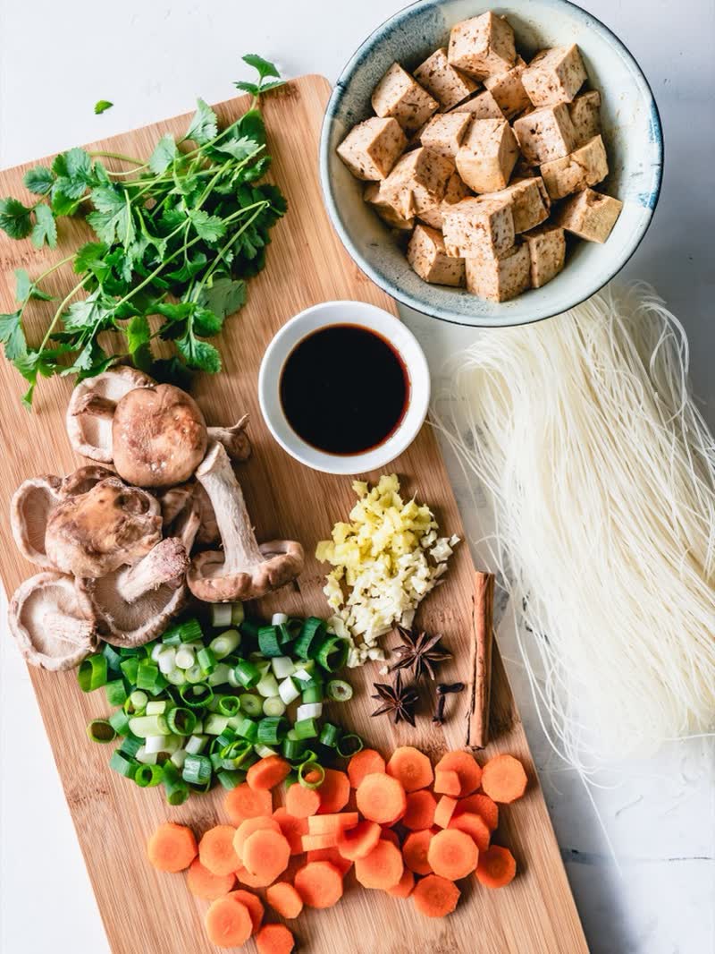 Wooden board with tofu, mushrooms, carrots and fresh herbs ready to cook